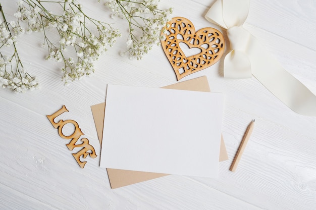 Brief mit einer Liebesbox in Form eines Herzens liegt auf einem weißen Holztisch mit Gypsophila-Blüten