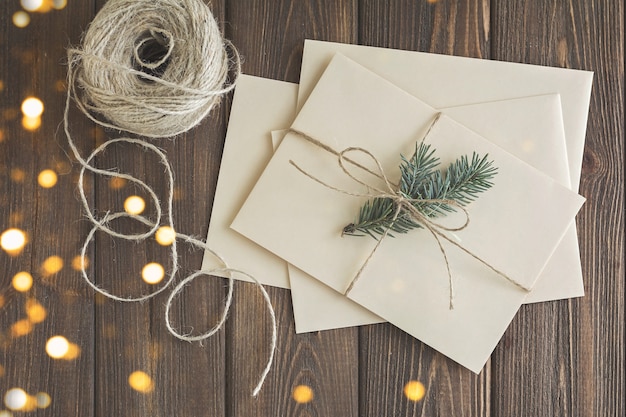 Foto briefe und weihnachtsdekoration auf braunem holztisch mit weihnachtslichtern.