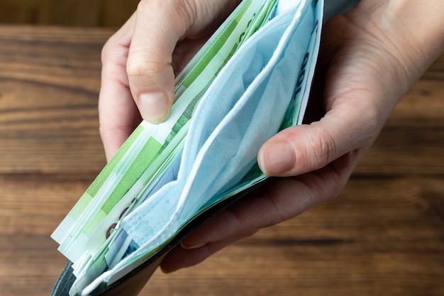 Foto brieftasche in händen mit geld und schutzmaske.