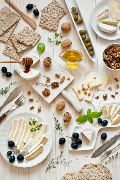 Briekäse und Camembert mit Nüssen und Trauben auf einem weißen hölzernen Hintergrund.