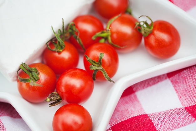 Briekäse- und Kirschtomaten auf roter Tischdecke. Nahansicht