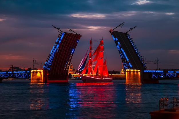 Brig con velas escarlata entre las partes abiertas del Puente del Palacio Noche Blanca San Petersburgo Rusia 24 de junio de 2022