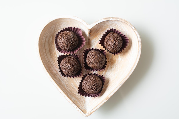 Brigadeiro, una bola de chocolate tradicional brasileña dulce en una vista superior de la placa en forma de corazón