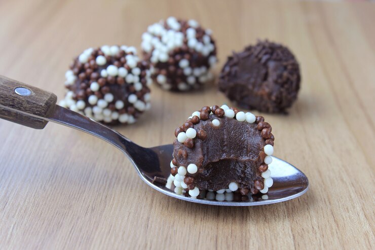 Foto brigadeiro (brigadeiro), chocolate doce típico da culinária brasileira coberto com partículas, em um fundo de madeira