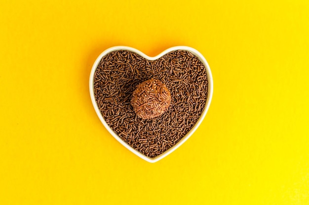 Brigadeiro en cuenco en forma de corazón sobre fondo amarillo