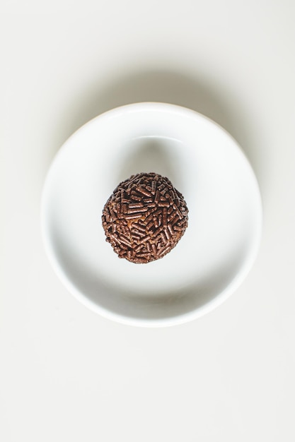 Brigadeiro, doce tradicional brasileiro, em um prato, fundo branco, vista de cima