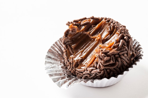 Brigadeiro mordido, un dulce brasileño, sobre un fondo blanco.