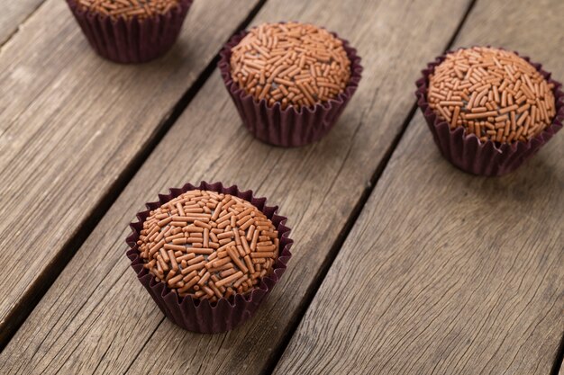 Brigadeiros típicos brasileños, varios sabores sobre mesa de madera.