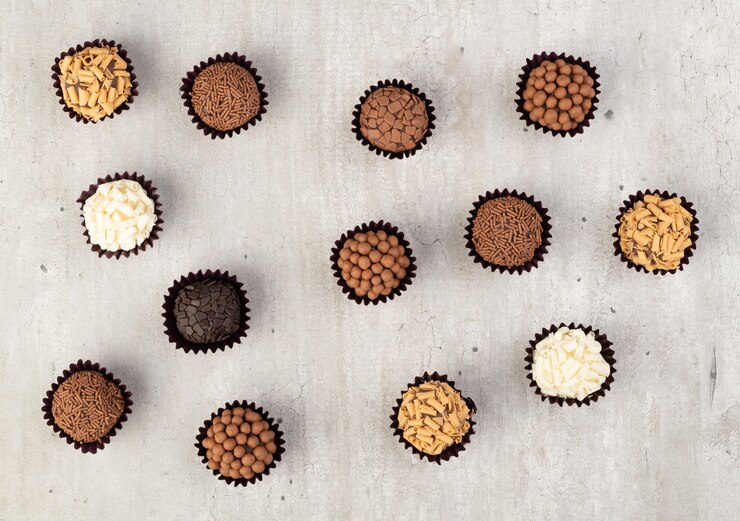 Foto brigadeiros típicos do brasil, vários sabores sobre uma mesa de madeira.