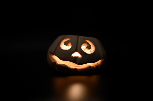 Foto brillante cara sonriente calabaza de halloween, candelabro, aislado sobre fondo negro oscuro de la noche