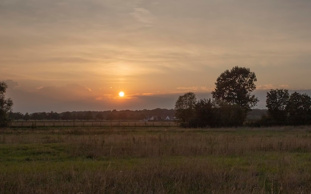 brillante puesta de sol en el campo de verano con heno y nubes