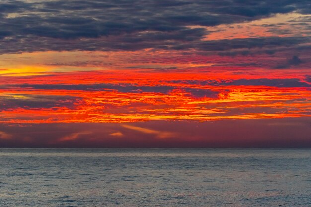 brillante puesta de sol dramática con rayas de naranja en el cielo de la noche sobre el mar