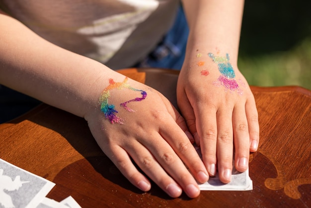 Foto brillante tatuaje de purpurina brillante en la mano de un niño en una fiesta de cumpleaños