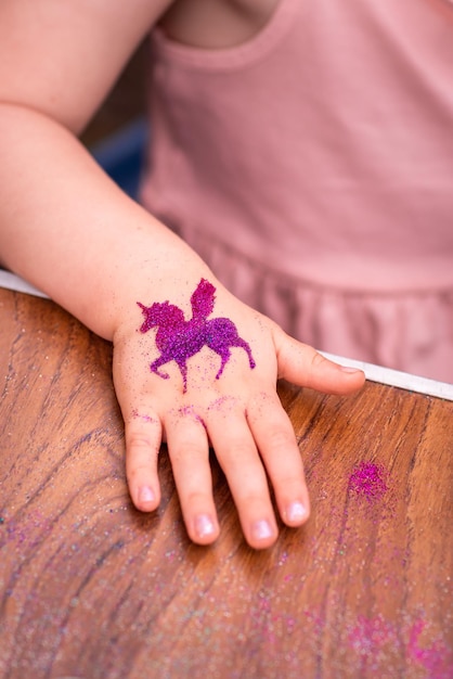 Brillante tatuaje de purpurina brillante en la mano de un niño en una fiesta de cumpleaños