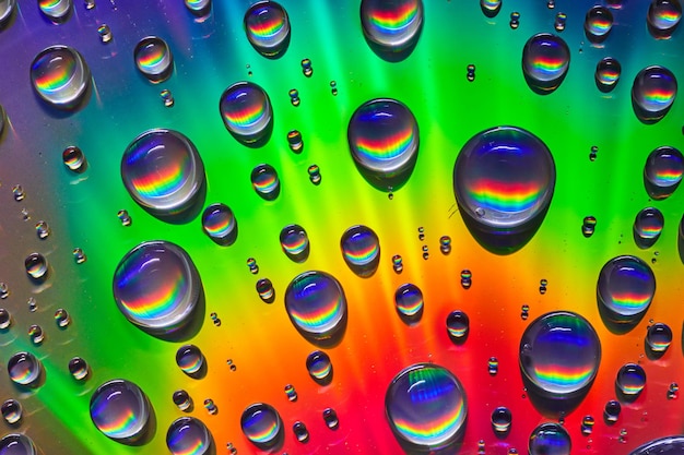 Brillanter Regenbogen aus Farben auf metallischer Oberfläche und im Hintergrund Wassertröpfchen