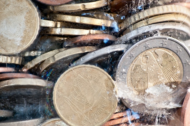 Foto brillantes monedas de euro congeladas en hielo con moneda alemana en frente