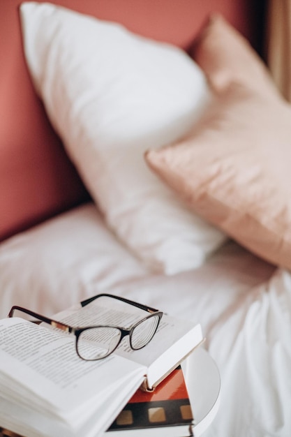 Brille auf einem Buchlesekonzept Haus Schlafzimmerbett mit Kissen und Nachttisch