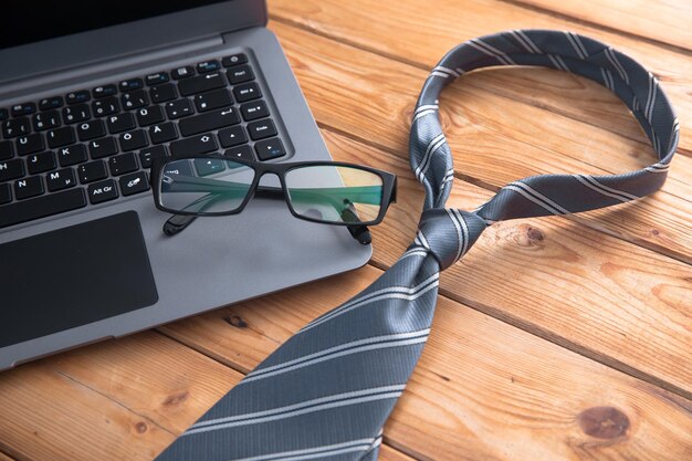 Brille auf Laptop und Krawatte auf dem Tisch