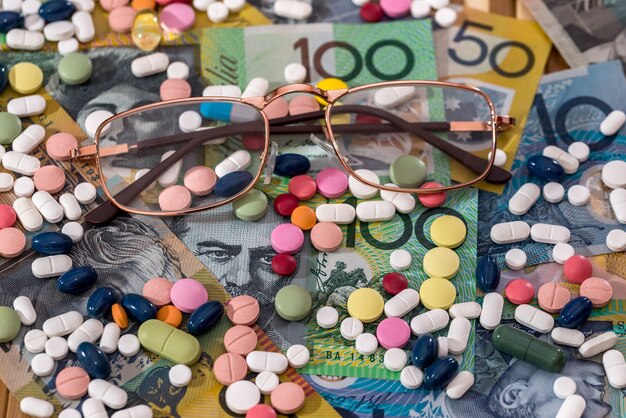 Brille mit bunten Pillen auf australischen Dollar