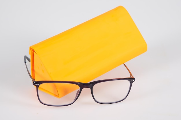 Brille optisch neu und orange Etuipyramide auf grauem Grund