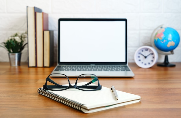 Brille und Notizblock mit Laptop-Computer mit leerem Bildschirm an Deck, Arbeitsplatz mit Laptop auf dem Tisch zu Hause, Arbeitsform-Home-Konzept