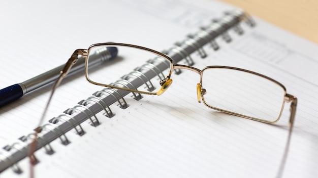 Brille und Stift auf einem offenen Notizbuch