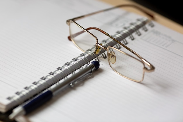 Brille und Stift auf einem offenen Notizbuch