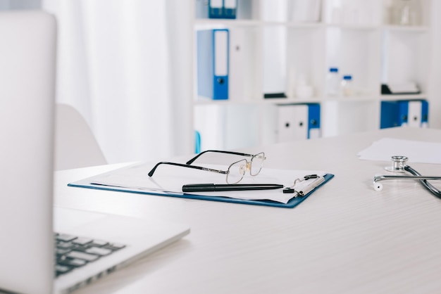 Foto brille und stift in der zwischenablage auf dem arbeitstisch in der klinik