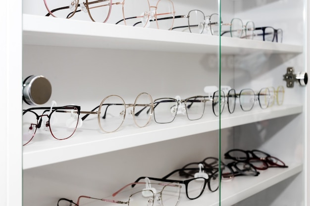 Brillen im optischen Geschäft, Mode, verschiedene Gläser auf weißem Regal im Einkaufszentrum. Brillenreihe bei einem Optiker, selektiver Fokus