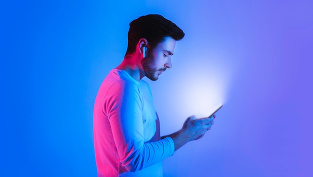 Brillo de teléfono en las manos de un tipo con auriculares inalámbricos perfil de espacio libre