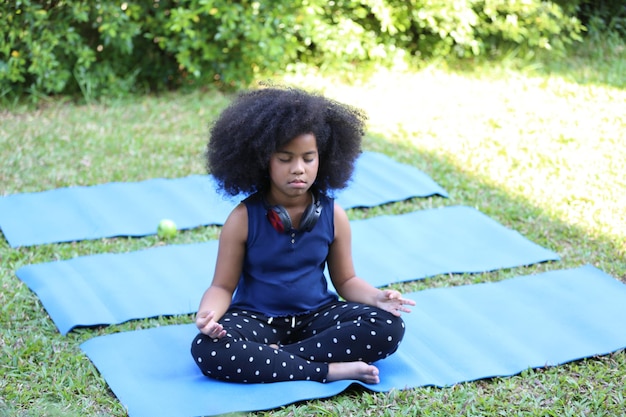 Brincadeira de criança afro e ioga ao ar livre.