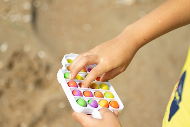 Brincadeira de criança com novo brinquedo de silicone pop na praia Covinha simples em moldura de plástico