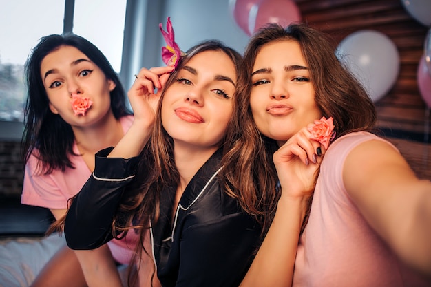 Brincalhão e simpáticas jovens posando. garota à direita, espere. modelos estão no quarto. muitos balões coloridos estão por trás deles.