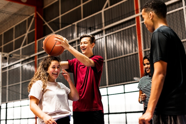 Brincalhão grupo de amigos do adolescente em uma quadra de basquete