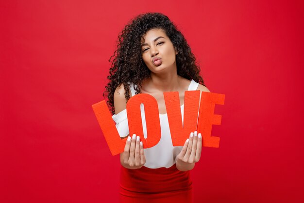 Brincalhão mulher negra segurando cartas de amor isoladas em vermelho