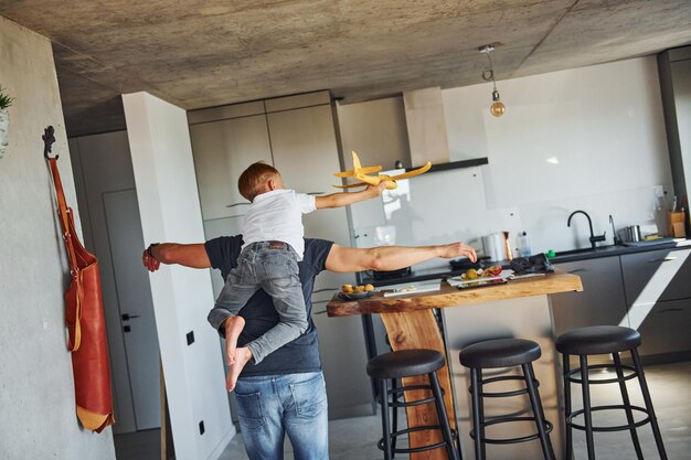 Brincando com avião de brinquedo amarelo Pai e filho estão dentro de casa juntos