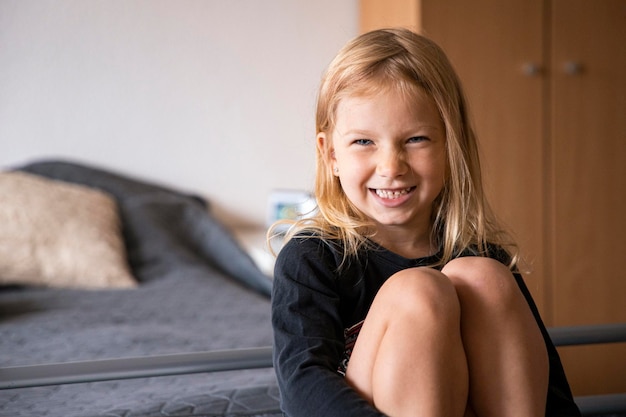 Foto brincando de uma menina loira fazendo careta sentada no sofá da sala