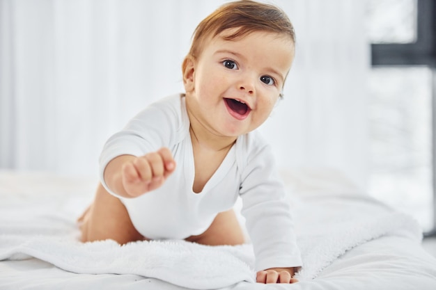 Brincando na cama Bebezinho está dentro de casa na sala doméstica