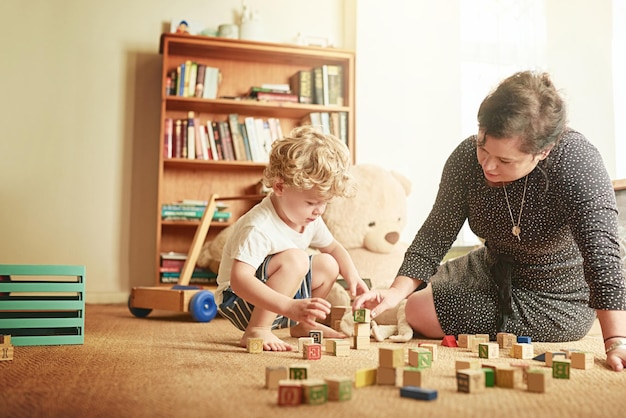 Brincar é uma maneira vital de aprender Foto de uma mãe e seu filho brincando com blocos de madeira em casa