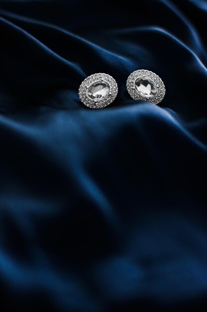 Brincos de diamante de luxo em fundo de seda azul escuro presentes de glamour de férias