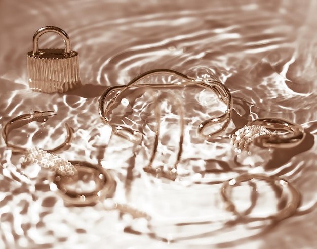 Brincos de pulseiras de ouro anéis de joias em fundo de água dourada glamour de luxo e design de beleza de férias para anúncios de marcas de joias