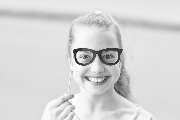 Brinde a cada niño una infancia feliz Adorable niño pequeño con una sonrisa feliz y una mirada divertida a través de los accesorios de las gafas Niña feliz con una gran sonrisa en el día de verano Feliz día internacional del niño