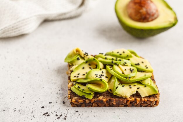 Brinde do abacate em um pão saudável do sésamo com sementes de sésamo, vista superior. Conceito de comida saudável vegan.