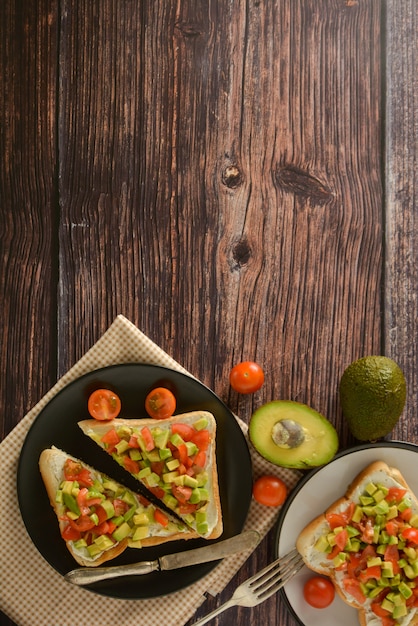 Brinde saudável com abacate, tomate cereja e queijo em um prato. Mesa de madeira.