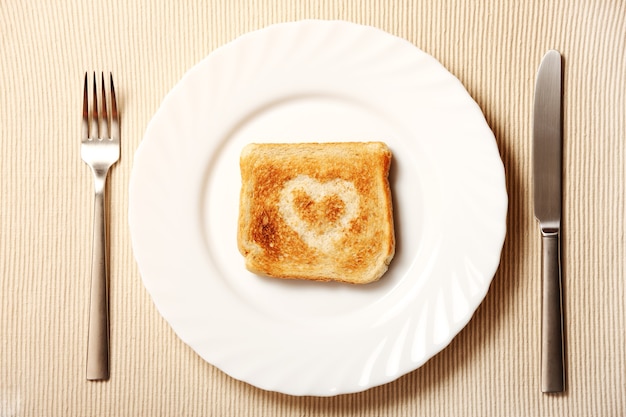 Un brindis con un corazón en un plato y cubiertos