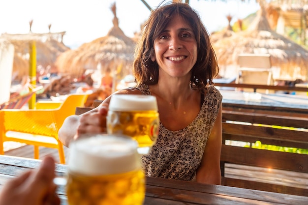 Brindis de una pareja en la playa en verano tomando unas cervezas en las vacaciones de verano