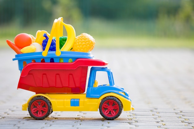 Foto brinque a cesta levando do caminhão do carro com brinquedo frutas e legumes.