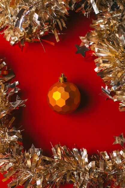 Brinquedo bola de Natal laranja em fundo vermelho