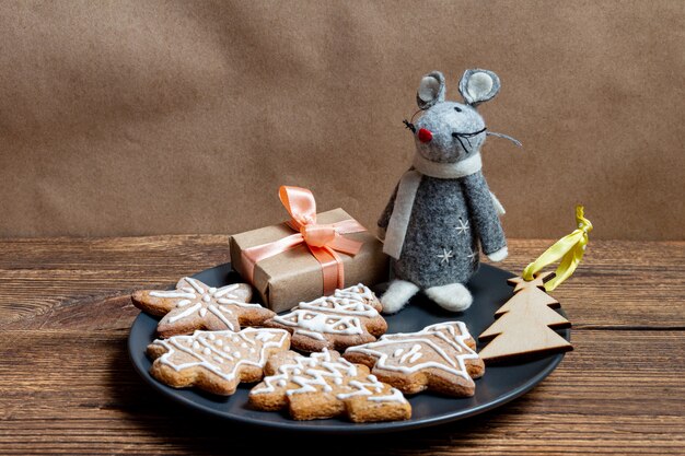 Brinquedo bonito rato cinzento no prato escuro com os biscoitos de Natal