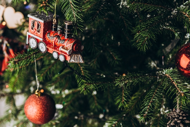 Brinquedo de ano novo: um trem antigo pendurado e bolas vermelhas em uma árvore de natal. conceito de natal e ano novo.